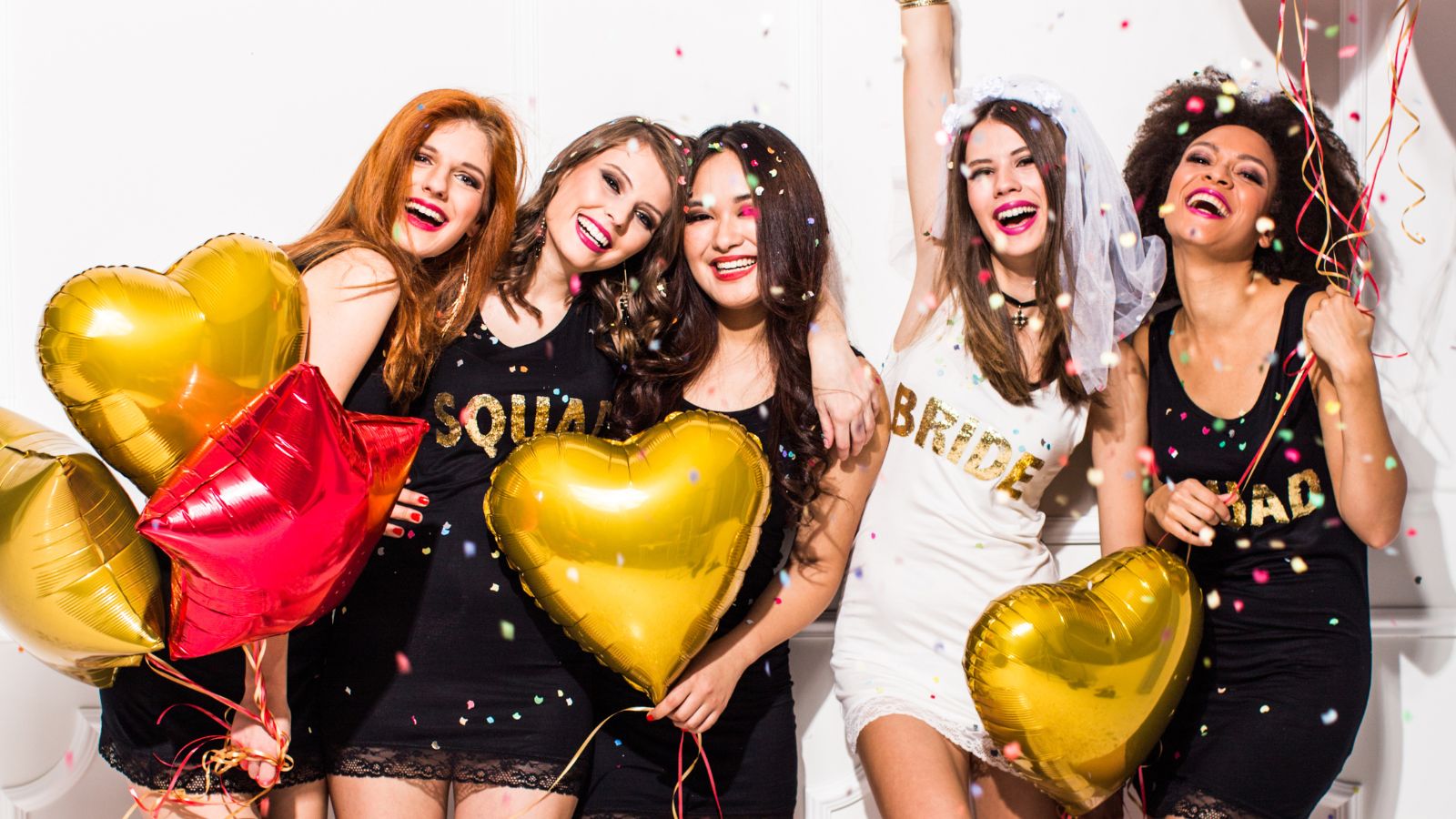 The hens party the bride ranks above the wedding — 10 women mid-toast, bride laughing hardest, champagne tower, purple-gold light